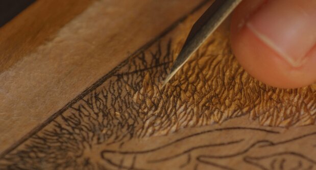 Un artisan à l’œuvre. On le voit travailler en reprenant des techniques ancestrales de gravure pour un projet de reproduction d’estampes shunga. (© 2023 Shunga Production Committee)