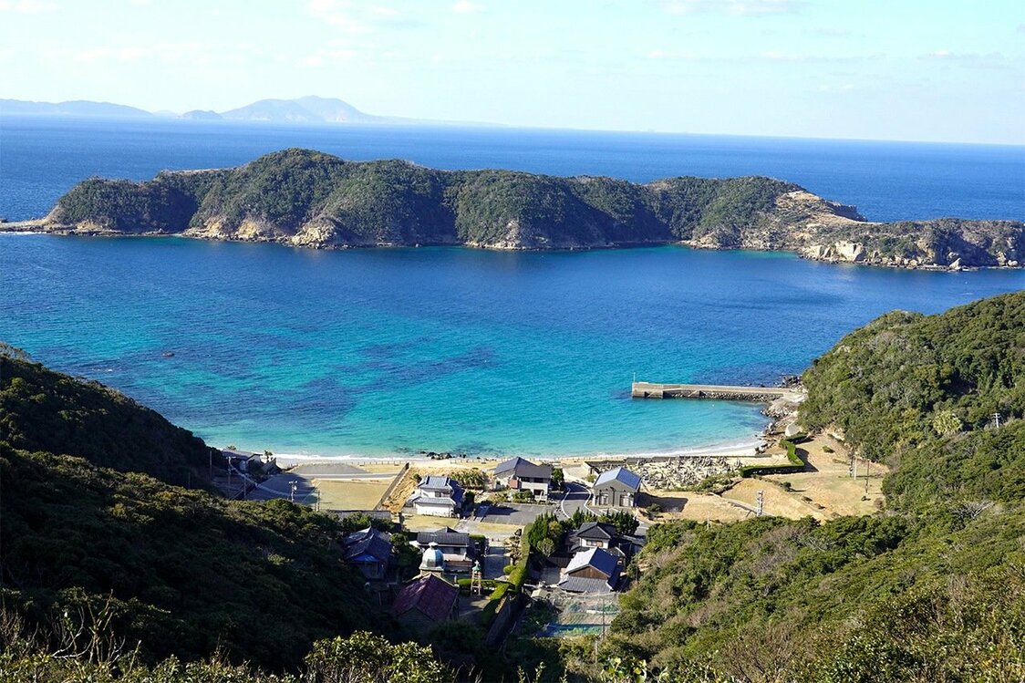 島北部の入り江に面した頭ヶ島集落。天主堂は集落の奥、緩やかに傾斜する山裾に立つ。石は正面に浮かぶ小島から切り出した　写真＝天野久樹