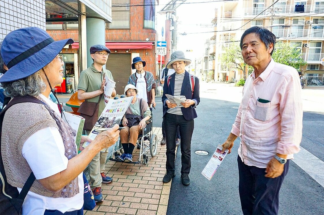 桜本地区を歩き始めたツアーの参加者たち。三浦さん（右）はヘイトスピーチとハルモニたちの闘いの歴史も伝える（川崎市川崎区）