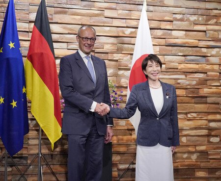 Japanese Prime Minister Sanae Takaichi (right) and German Chancellor Friedrich Merz (left) shake hands at the prime minister's office in Tokyo on Wednesday
