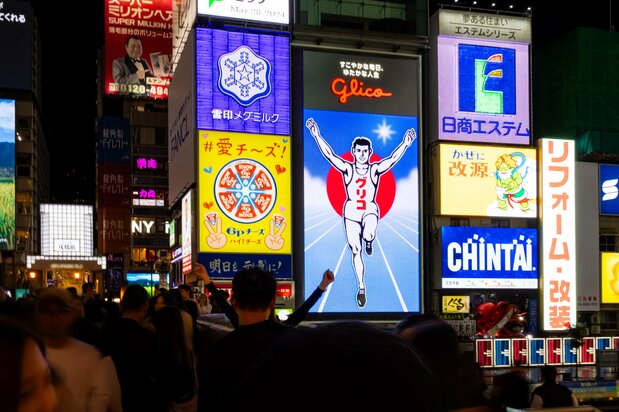 El anuncio se ilumina media hora después de la puesta del sol. La “pose Glico” consiste en levantar ambos brazos y la pierna izquierda.