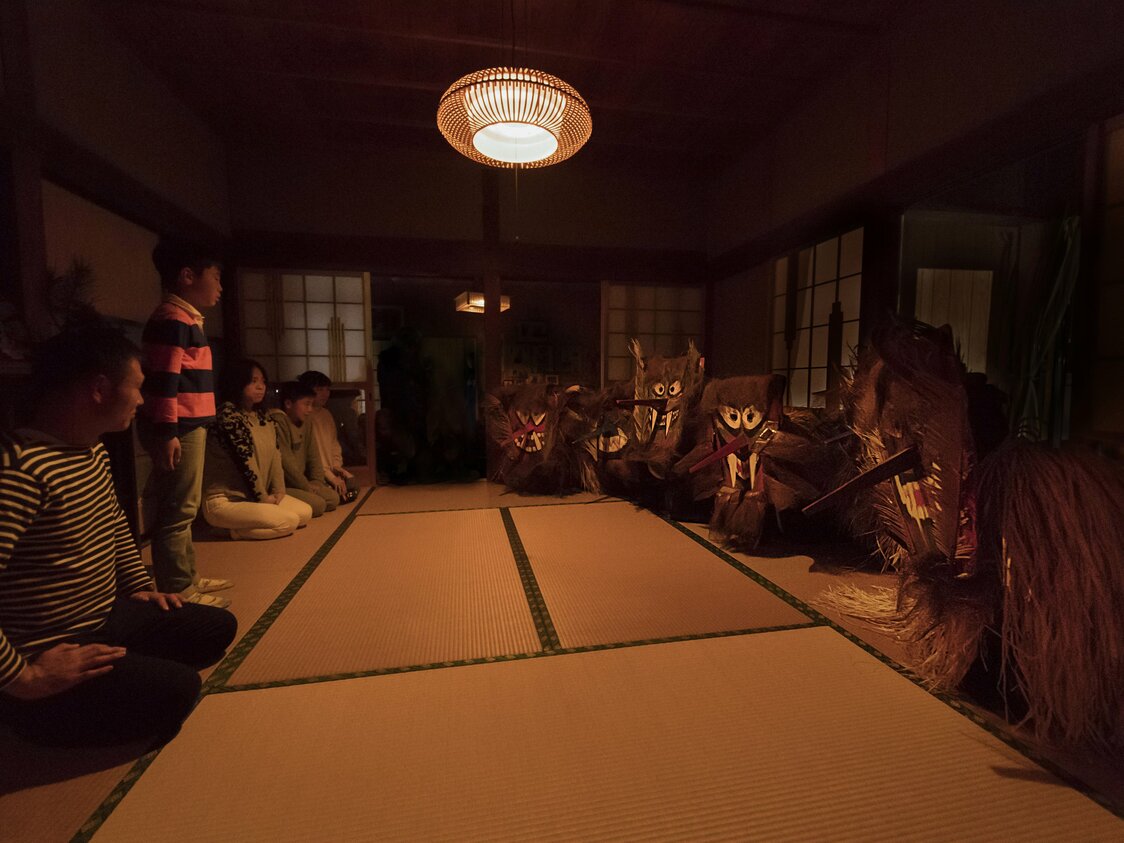 薄暗い部屋で、気をつけの姿勢でトシドンの言うことを聞く男の子