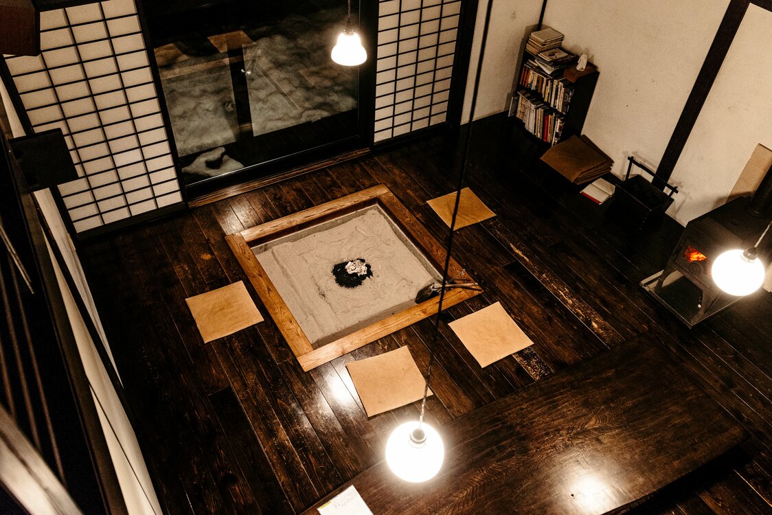 黒漆を塗った板張りの座敷には、炉と薪ストーブ
