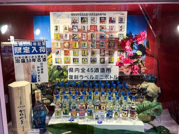 沖縄本土復帰50周年の今年、沖縄県物産公社の「銀座わしたショップ本店」では県内全45酒造所復刻ラベルミニボトルをガラスケース内に展示している(2022年7月28日、東京・銀座1丁目で評者撮影)
