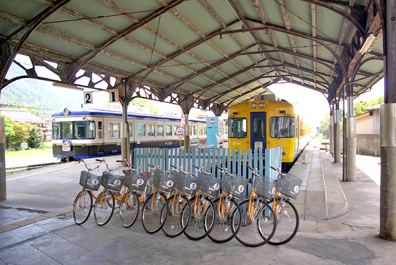 Bicycles wait for riders at a train station.