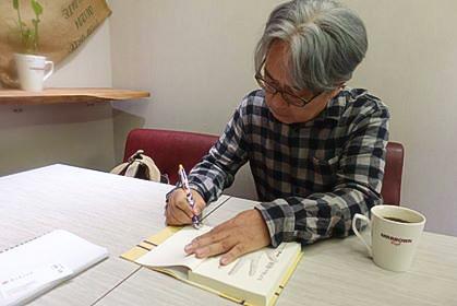 著書にサイン中の木下氏(筆者提供)